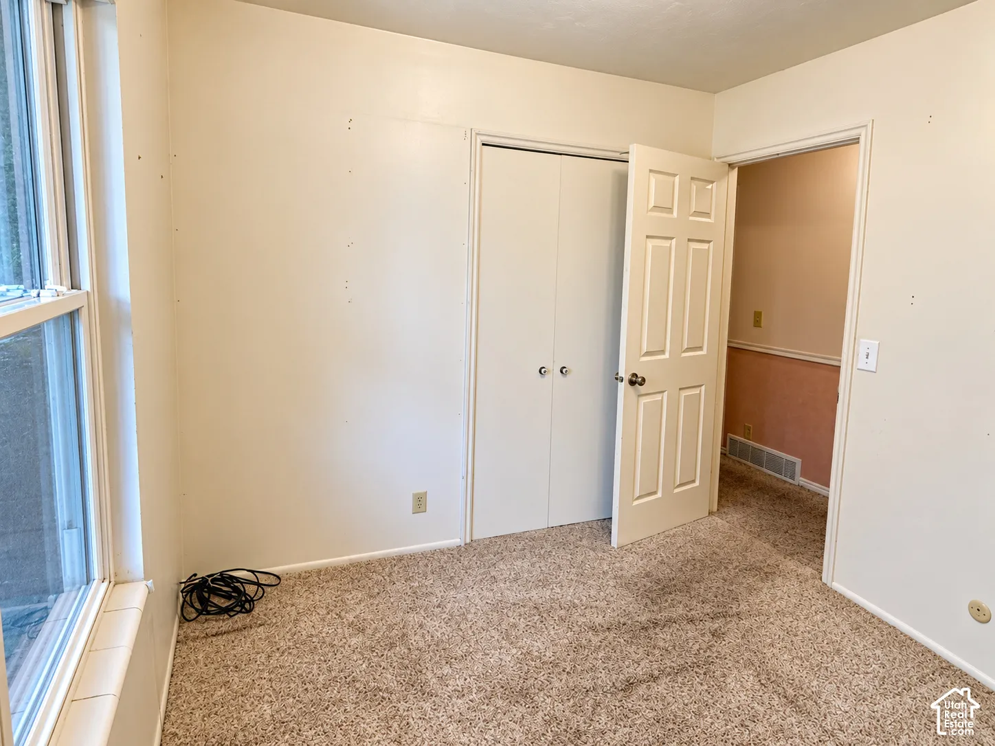 Neutral-toned wall-to-wall carpeting, double-panel closet doors, and multi-pane vertical window