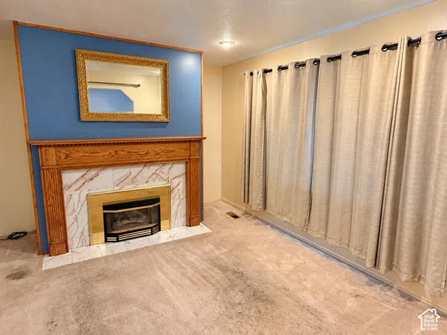 Fireplace featuring a wood mantel, stone-tile surround, and gold-finish metal firebox, accented by a bold blue wall and recessed ceiling lighting