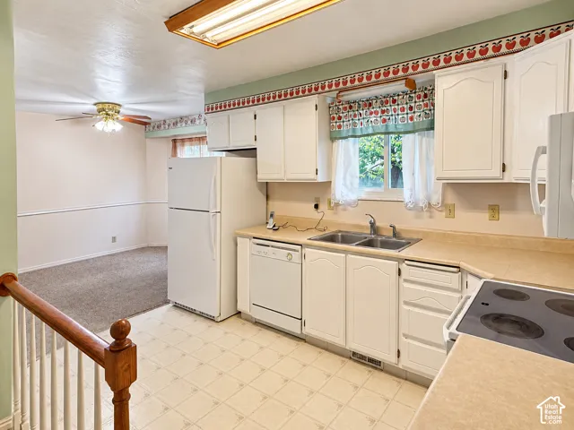 Kitchen featuring white cabinetry, solid-surface countertops, dual-basin stainless steel sink, built-in dishwasher, and electric cooktop