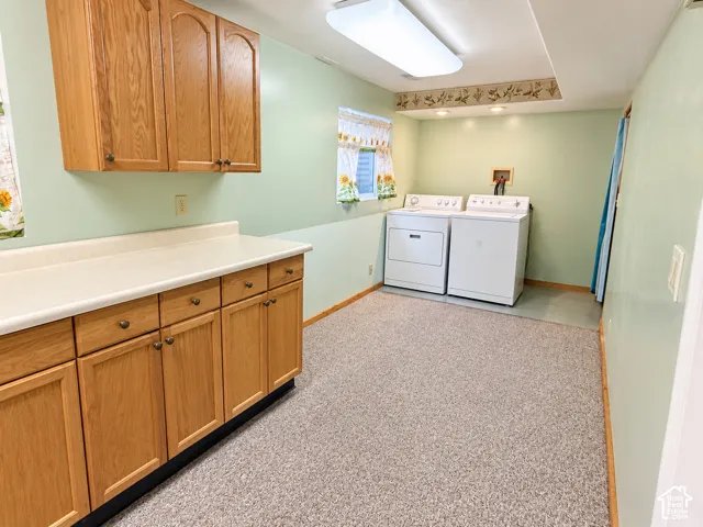 Laundry space featuring oak cabinetry, a solid-surface countertop, textured carpeting, and a flush-mount overhead light fixture
