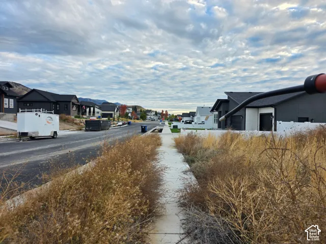 Concrete sidewalk with paved asphalt street and surrounding residential architecture featuring dark exterior siding and mountain backdrop