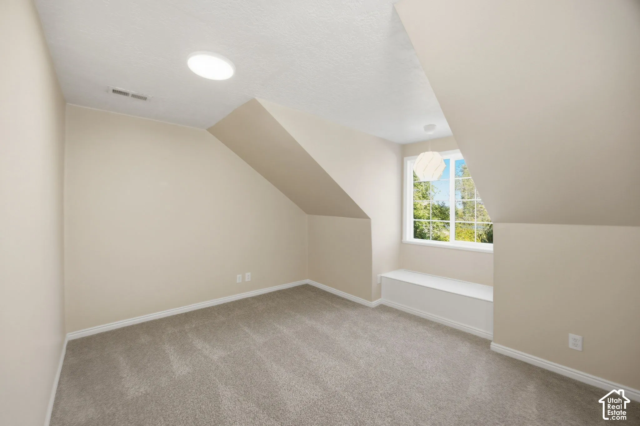 Sloped ceilings, built-in window seat, neutral carpeting, recessed ceiling lighting, and multi-pane window