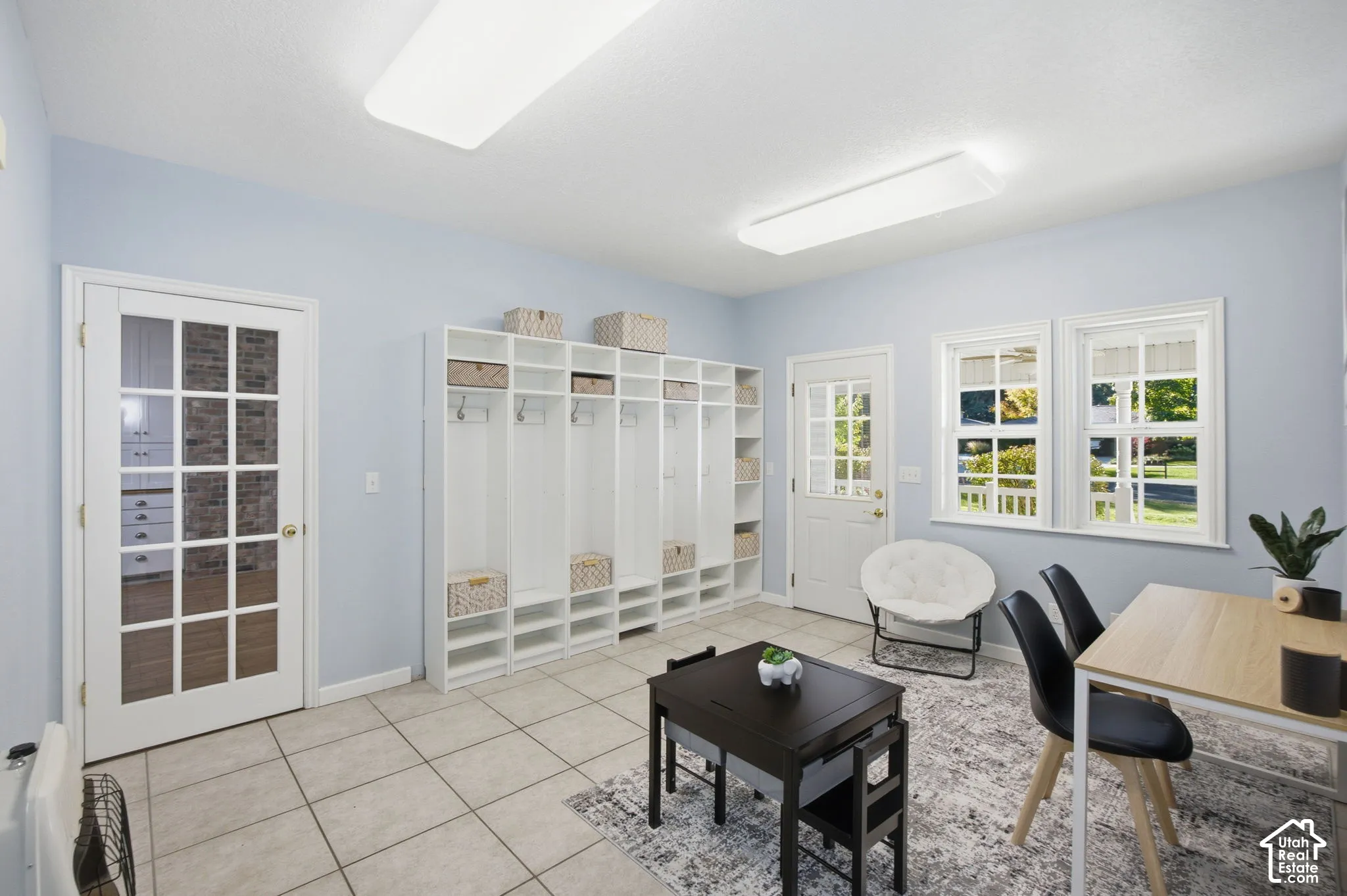 Ceramic tile flooring, built-in floor-to-ceiling cabinetry with individual storage cubbies, and a glass-paneled French door