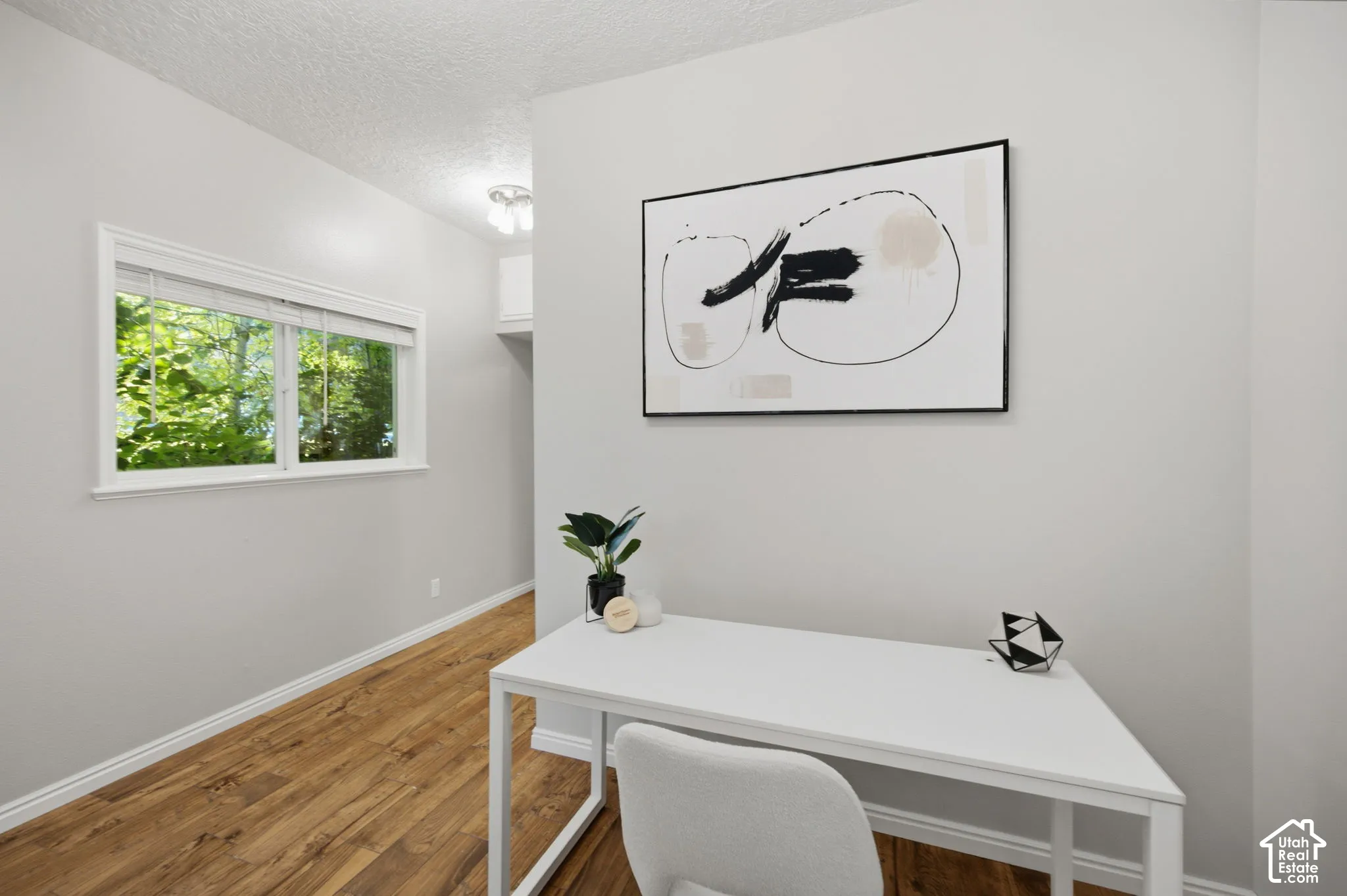 Neutral-toned interior space featuring wood-finish flooring, a dual-pane horizontal window, and a ceiling-mounted light fixture