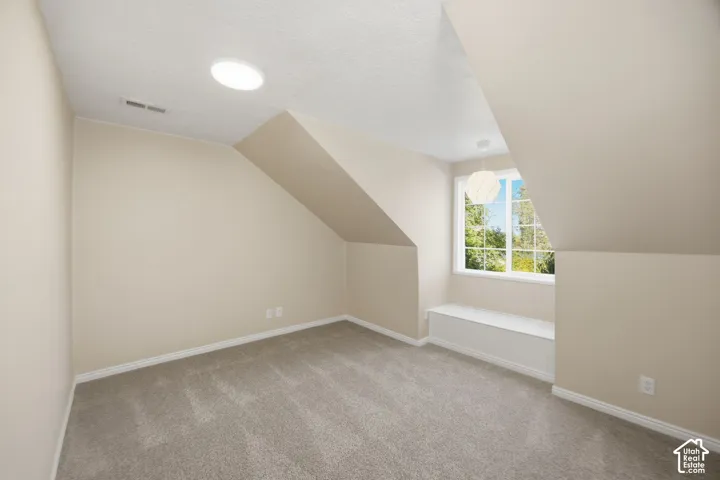Sloped ceilings, built-in window seat, neutral carpeting, recessed ceiling lighting, and multi-pane window