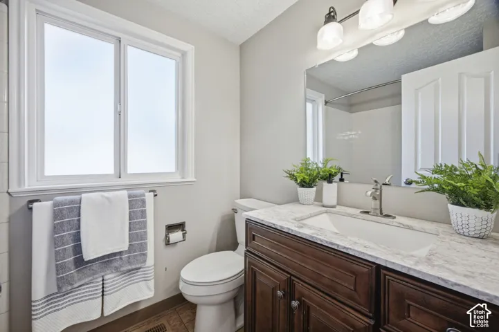 Bathroom featuring a dark wood-finish vanity, stone-patterned countertop, integrated basin, brushed metal faucet, and wall-mounted vanity lighting