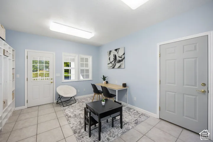 Room featuring large-format ceramic floor tile, dual exterior entry doors, built-in shelving, and multi-pane windows