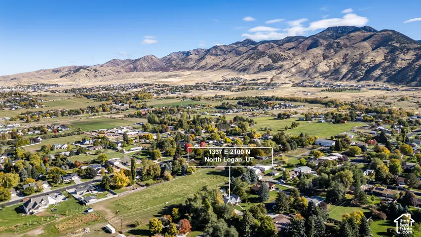 Aerial perspective featuring expansive open grounds, mature trees, and a mountain range backdrop