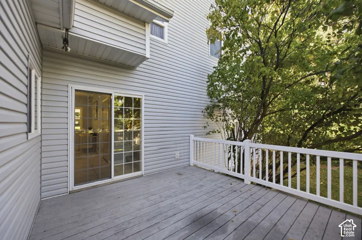 Exterior deck featuring wood-finish decking, a white vertical picket railing, horizontal vinyl siding, and sliding glass doors