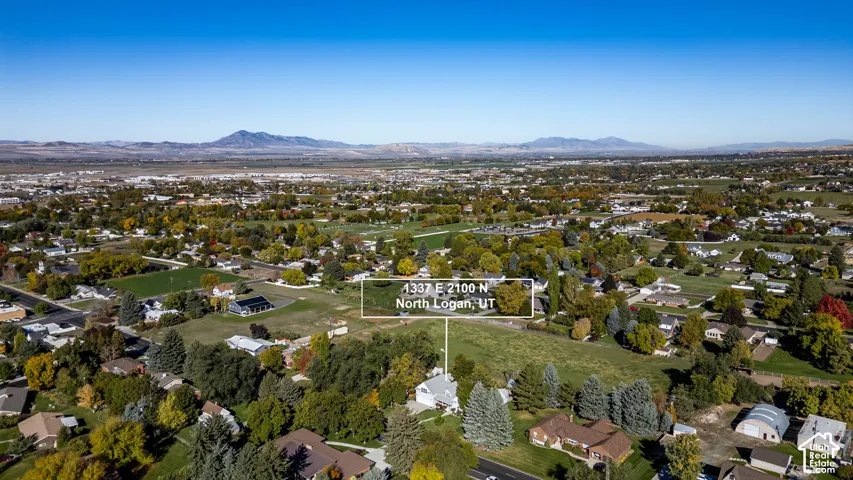 Aerial perspective featuring a residential lot with mature trees and expansive mountain backdrops