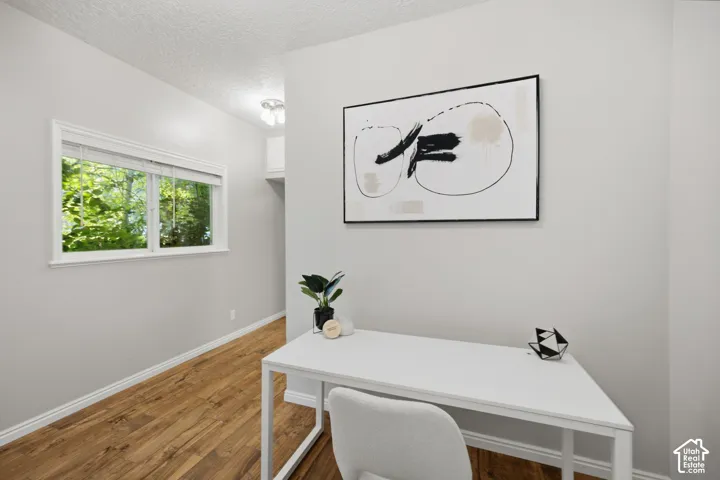 Neutral-toned interior space featuring wood-finish flooring, a dual-pane horizontal window, and a ceiling-mounted light fixture
