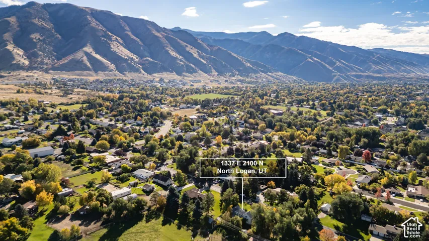 Aerial perspective featuring an expansive landscape with prominent mountain backdrops, mature trees, and established greenery