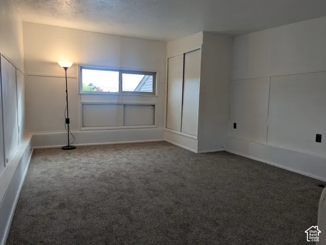 Neutral-toned wall-to-wall carpeting, white paneled wall accents, and built-in sliding door closet