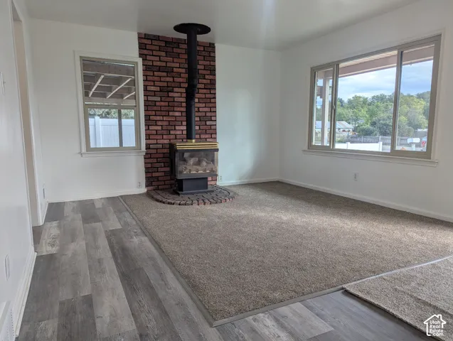 Interior space featuring a free-standing gas stove, exposed red brick chimney, expansive multi-pane windows, and wood-finish flooring