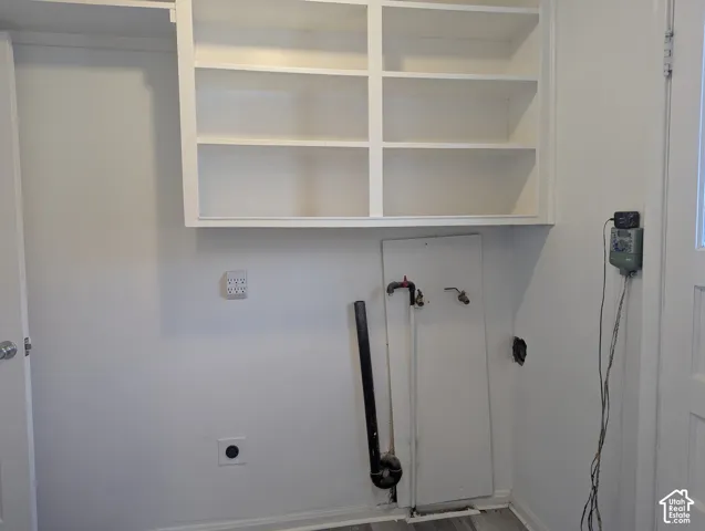 Built-in white overhead shelving and dedicated plumbing hookups for gas and electric laundry appliances