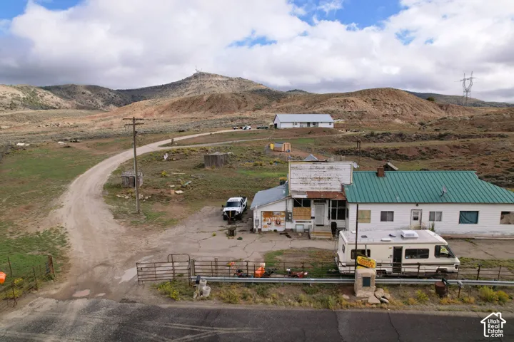 Expansive acreage featuring a metal-roof structure, gravel access road, metal gate entry, and prominent mountain surroundings