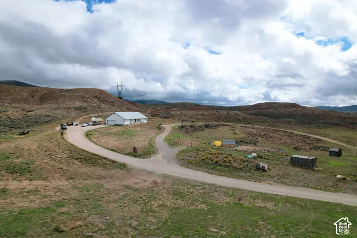 Expansive acreage featuring rugged topography, a single-story residence with a metal roof, and an extensive unpaved private drive