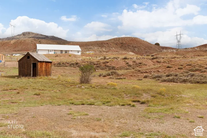 Expansive lot featuring native terrain, a wood-sided structure, and prominent mountain backdrops