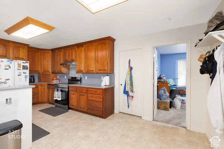 Kitchen featuring wood cabinetry, solid surface countertops, a stainless steel range, and tile flooring