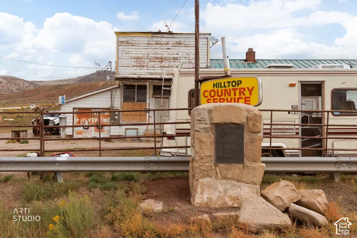 Commercial property featuring wood-siding exterior, metal roofing, metal perimeter fencing, and stone monument pillar