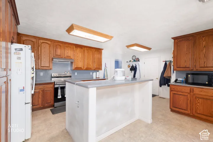 Kitchen featuring wood cabinetry, a central island with a countertop, tile flooring, and integrated lighting fixtures