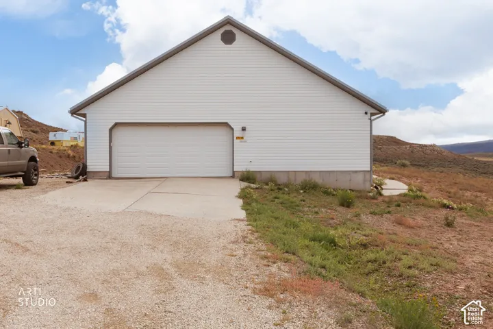 Detached garage structure with horizontal siding, a gabled roofline, and a concrete driveway