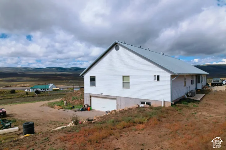 White vinyl siding exterior with a metal roof, concrete foundation, and an attached lower-level garage