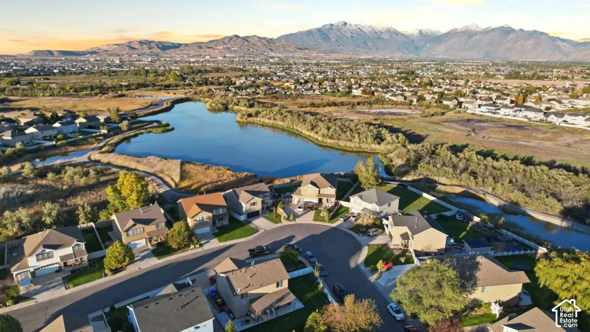 Aerial perspective of a residential neighborhood featuring a centralized water feature and a mountain range backdrop