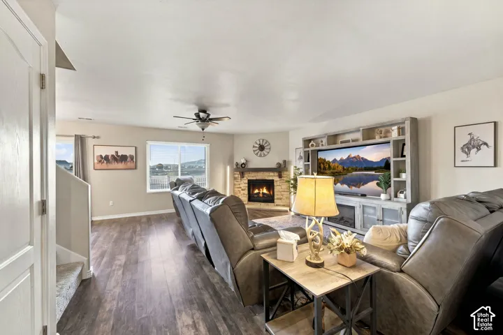 Living area featuring wood-finish flooring, a corner fireplace with stone-veneer surround, a built-in media console, and a ceiling fan