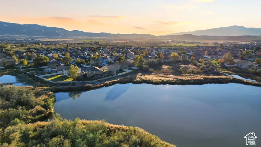 Aerial perspective featuring an expansive body of water, natural wetlands, and a mountain range backdrop