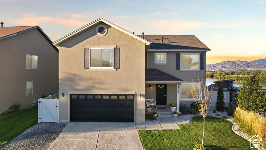 Two-story residence featuring a stucco exterior, attached two-car garage, concrete driveway, front porch, and mountain backdrop