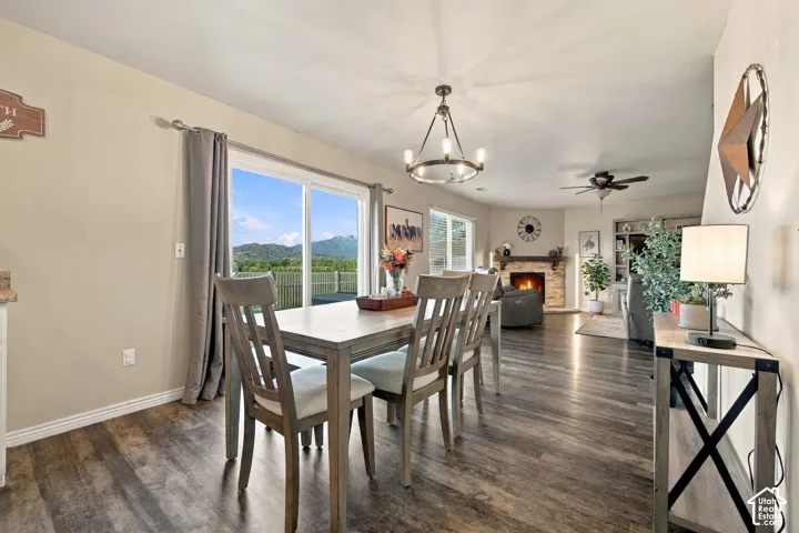 Open-concept space featuring wood-finish flooring, stone-surround fireplace, built-in shelving, wagon-wheel style chandelier, and sliding glass doors with a mountain backdrop