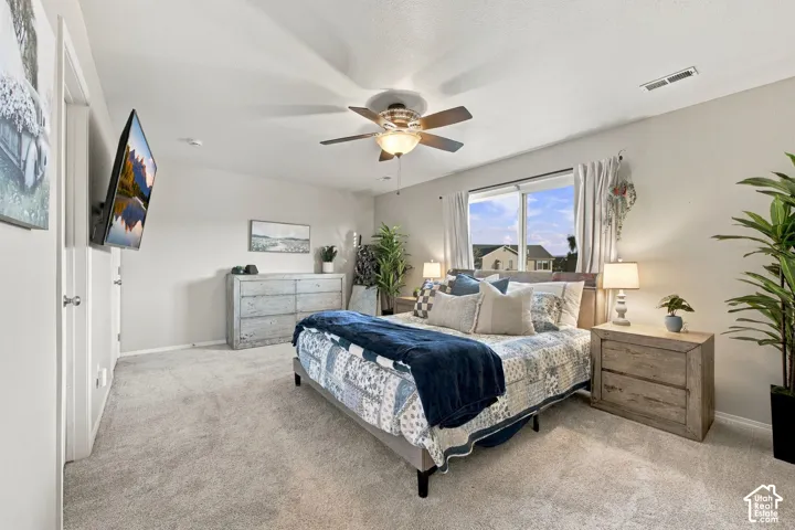 Neutral wall-to-wall carpeting, ceiling fan with integrated lighting, and large sliding window with exterior exposure