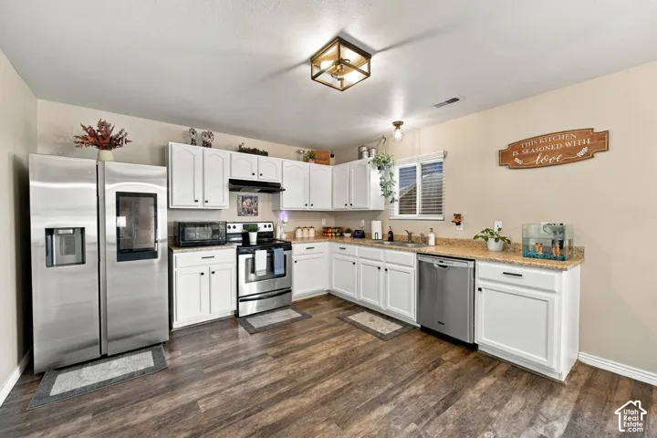 Kitchen featuring white cabinetry, wood-finish flooring, stone-composite countertops, stainless steel appliances, and a square flush-mount ceiling fixture