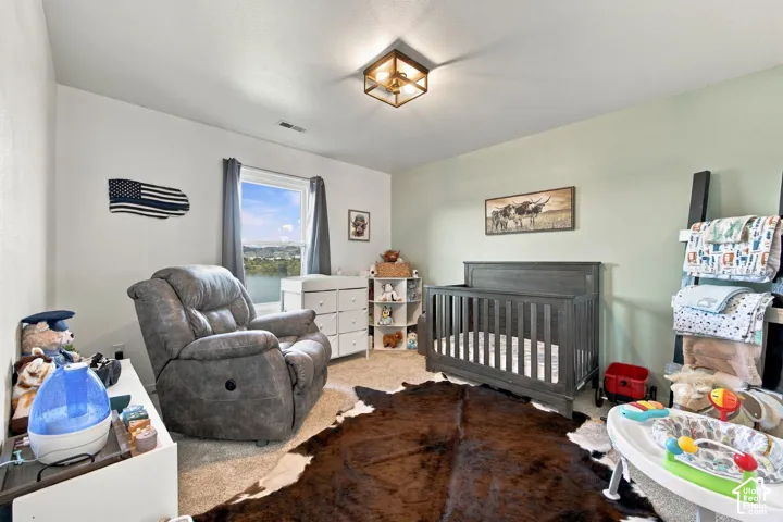 Bedroom featuring neutral wall paint, a light green accent wall, wall-to-wall carpeting, and a geometric-frame ceiling light fixture