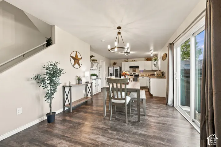 Open concept interior featuring wood-finish flooring, a multi-light chandelier, white shaker-style cabinetry, and sliding glass doors