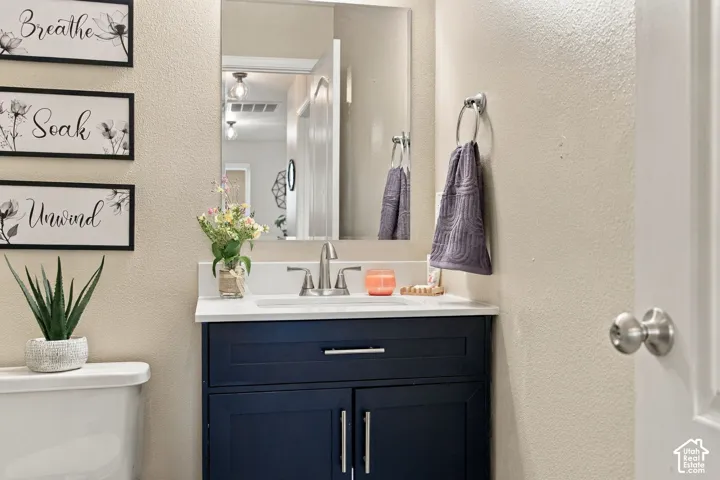 Navy blue vanity featuring polished hardware, a white countertop, an integrated basin, a centered faucet, and a wall-mounted mirror
