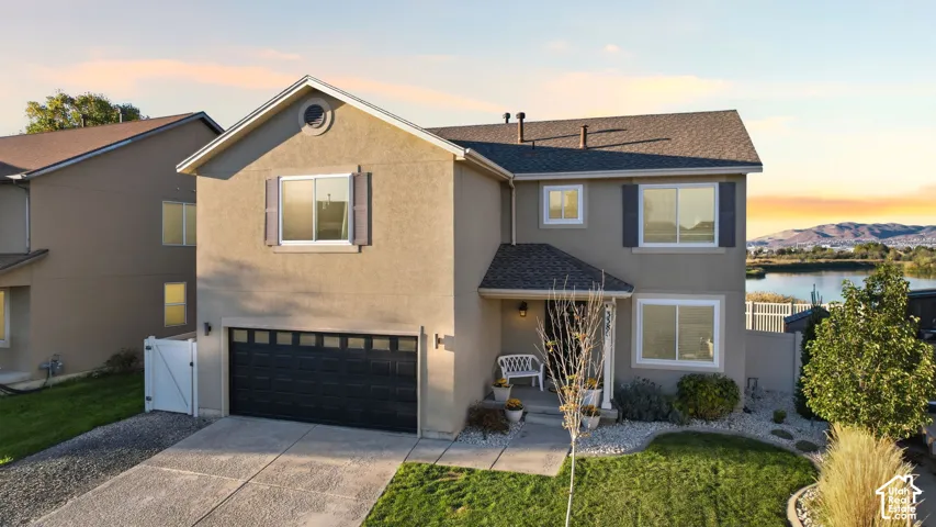 Two-story exterior featuring a stucco facade, gable roof, double-car garage with overhead door, concrete driveway, and landscaped front lawn
