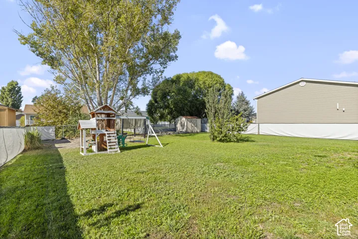 Expansive backyard featuring a large grass lawn, mature trees, privacy fencing, and a detached storage shed