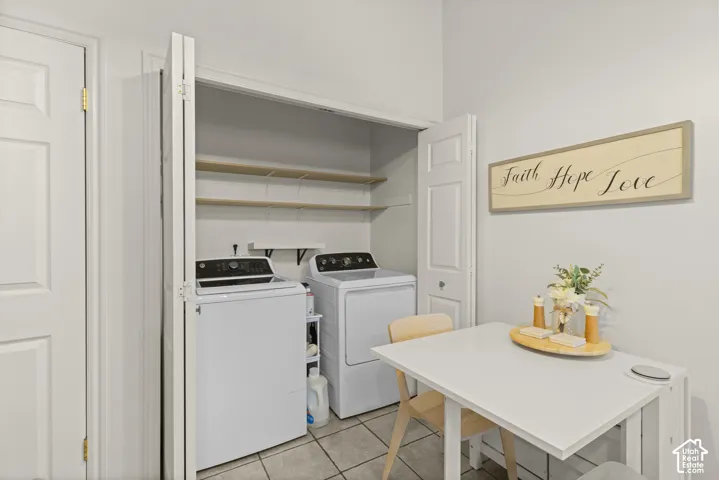 Laundry closet with bi-fold doors, tile flooring, and multiple built-in storage shelves