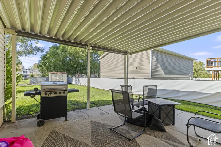 Covered concrete patio featuring a metal corrugated roof, expansive backyard, and perimeter privacy fencing