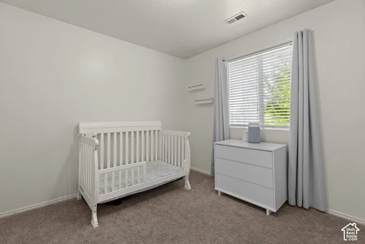 Neutral-toned interior featuring wall-to-wall carpeting, window with slatted blinds, and mounted wall shelving