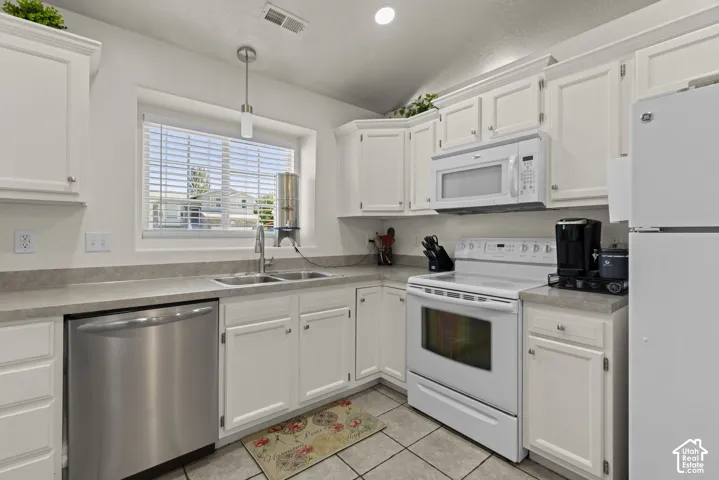 Kitchen featuring white cabinetry, solid surface countertops, stainless steel dishwasher, white range with integrated microwave, and tile flooring