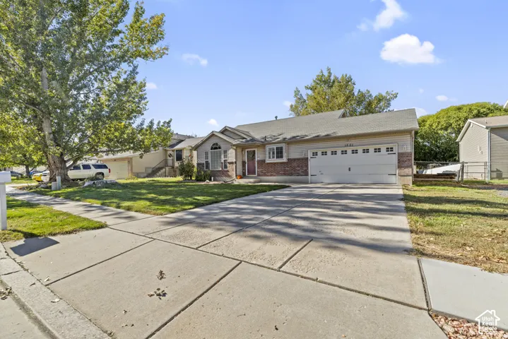 Single-story residence featuring a brick and horizontal siding exterior, attached two-car garage, concrete driveway, and mature landscaping