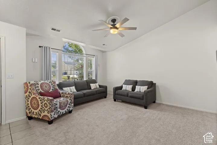 Vaulted ceilings featuring an arched window, neutral wall paint, and a central ceiling fan with integrated lighting