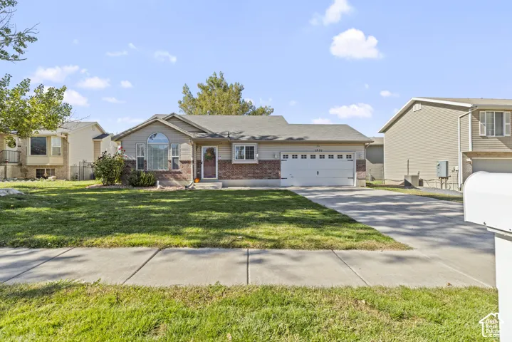 Single-story exterior featuring a brick and horizontal siding facade, attached two-car garage, concrete driveway, and arched window detail
