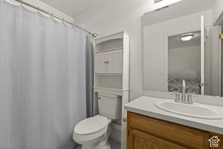 Bathroom featuring wood-finish vanity cabinetry, solid-surface countertop with an integrated oval sink, polished chrome widespread faucet, frameless wall-mounted mirror, and white built-in storage shelving