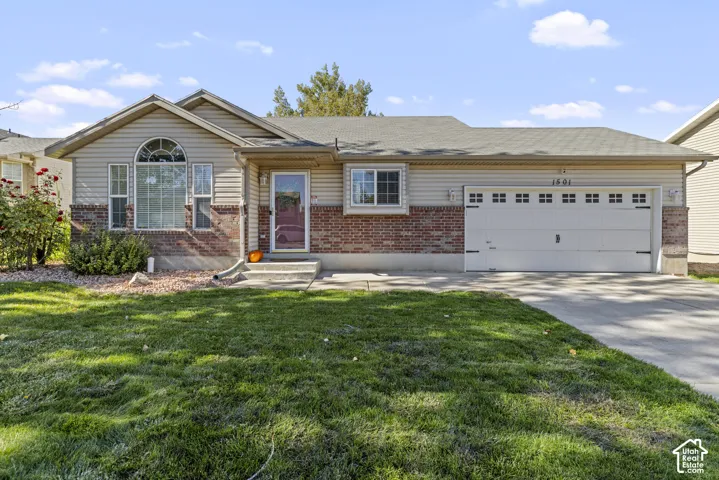 Single-story exterior featuring a brick and horizontal siding facade, arched window detailing, concrete driveway, and attached two-car garage