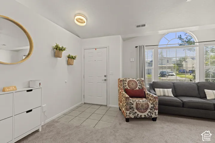 Entryway featuring tile flooring, neutral wall-to-wall carpeting, an arched window, and a white paneled door