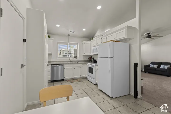 Kitchen featuring white cabinetry, stainless steel dishwasher, tile flooring, recessed lighting, and vaulted ceilings